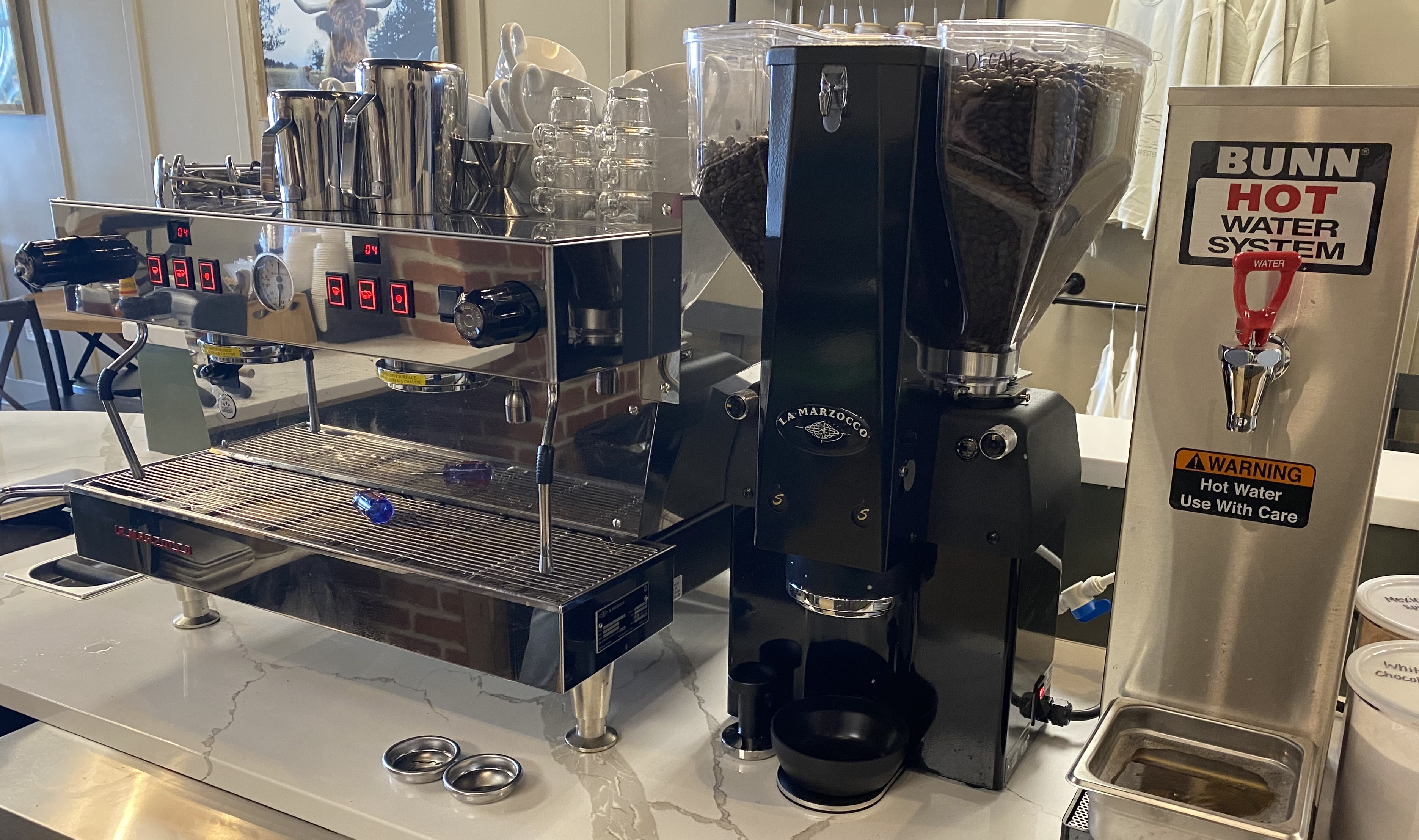La Marzocco espresso machine, commercial grinder, and Bunn hot water system on a cafe counter
